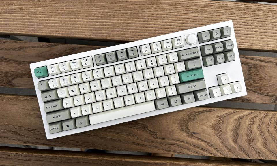 The Keychron Q3 Max mechanical keyboard in white rests on top of a brown wooden outdoor table.